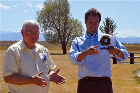 Governor Steve Bullock, right, is presented a pipe covered with quagga mussels at the Ronan checkpoint Friday by Rep. Mike Cuffe. 