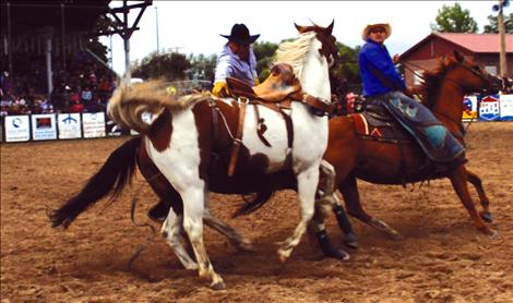 Pete White, right, leads the bucking horse out of the arena, while Bodge Whitworth trips the flank strap. 