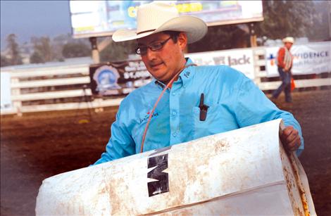 Carrying a barrel, Pete White works hard at the INFR Flathead River Rodeo. He still has his piggin string from competing in the tie down roping.