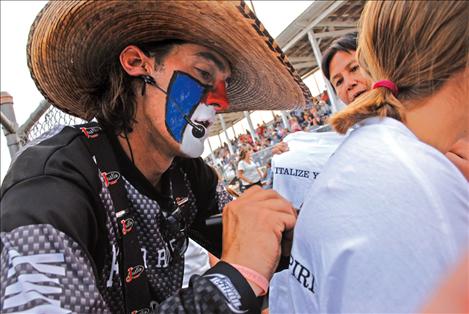 Rodeo clown Danger Dave autographs a young lady’s T-shirt at the Thursday night performance of the Flathead River Rodeo, and Indian National Finals tour rodeo. Legend had it Dave Whitmoyer played  football for the Carroll College Saints and is a hunting guide when he’s not performing at rodeos. 