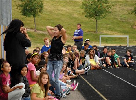 Polson Middle School sixth graders sit on the track as they listen to speakers at the Graduation Matters kickoff. 