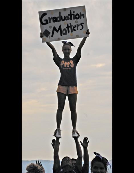 Polson cheerleader Alicia Sicz holds a Graduation Matters sign as she stands on the hands of another member of the squad.