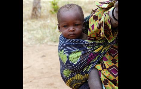 A Kenyan baby and mother pause in their daily chores. In Kenya the national language is Swahili, but each tribe has its own language.