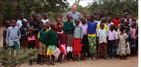 Kenyan children stand with Jack Stivers in front the orphanage. Clothes and shoes are constant needs, as well as medical care and glasses.