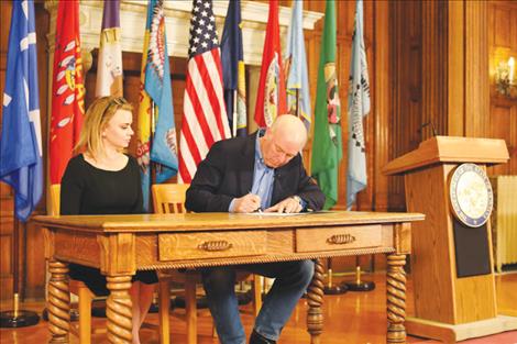 Governor Gianforte, seated beside Director of Administration Misty Ann Giles, signs a letter authorizing the investment of over $309 million to expand broadband access