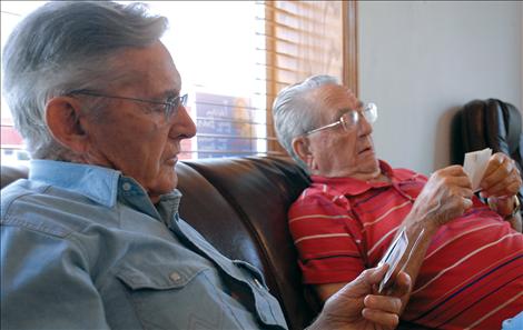 Bill Hocker and Phil Maxwell look over old  pictures as they reminisce about enlistment during World War II.