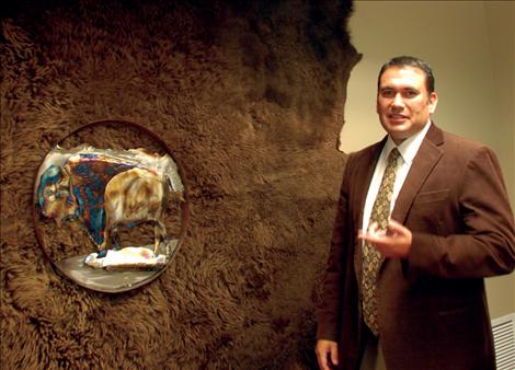 Robert DePoe stands by a buffalo robe and a metal art piece of a buffalo. He chose the items because the Salish Kootenai College mascot is the bison